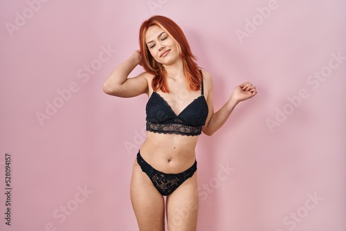 Young caucasian woman wearing lingerie over pink background stretching back  tired and relaxed  sleepy and yawning for early morning