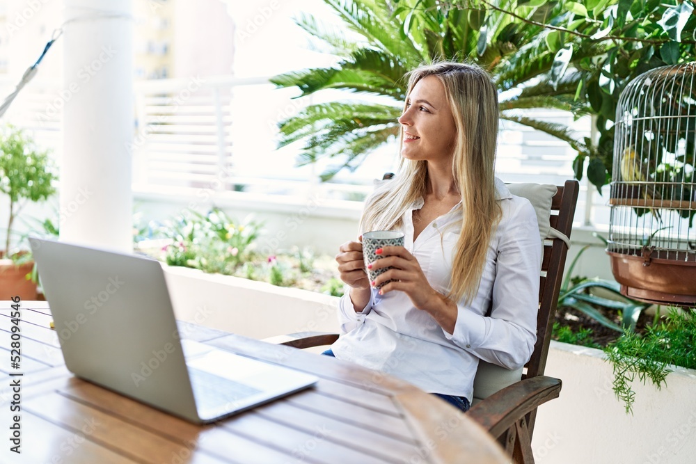 Young blonde woman drinking coffee using laptop working at the terrace. Young blonde woman drinking coffee using laptop working at the terrace.