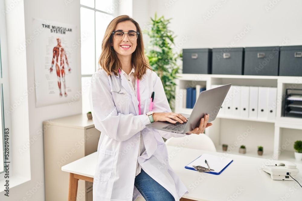 Young woman wearing doctor uniform using laptop at clinic Young woman wearing doctor uniform using laptop at clinic