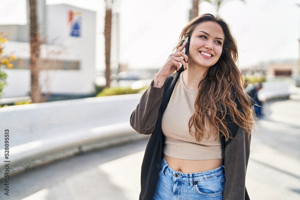 Fototapeta premium Young beautiful hispanic woman smiling confident talking on the smartphone at park