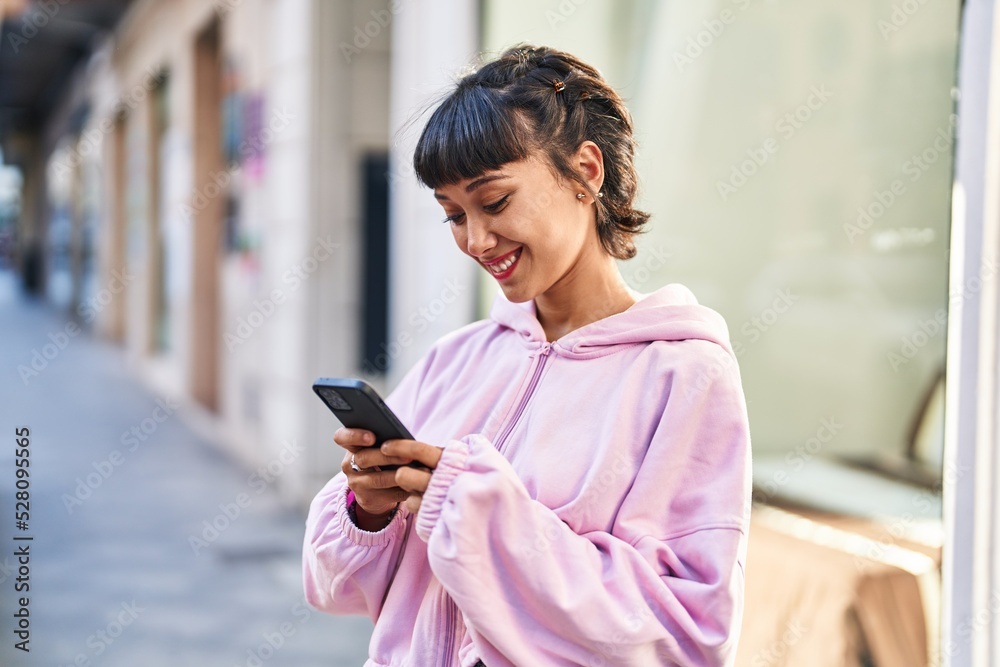 Young woman smiling confident using smartphone at street