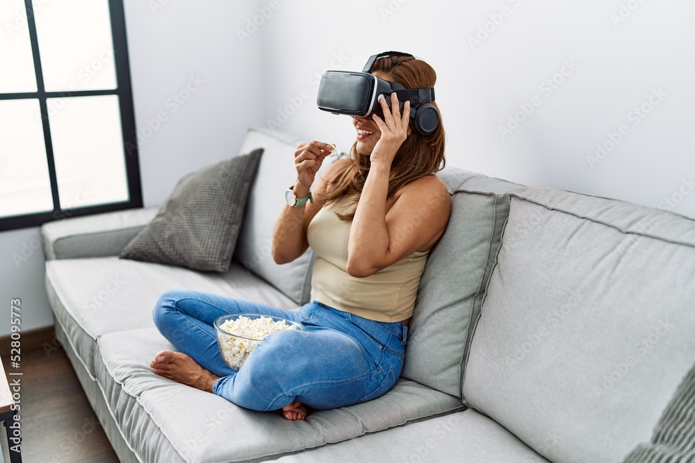 Young latin woman watching movie using virtual reality glasses at home Young latin woman watching movie using virtual reality glasses at home