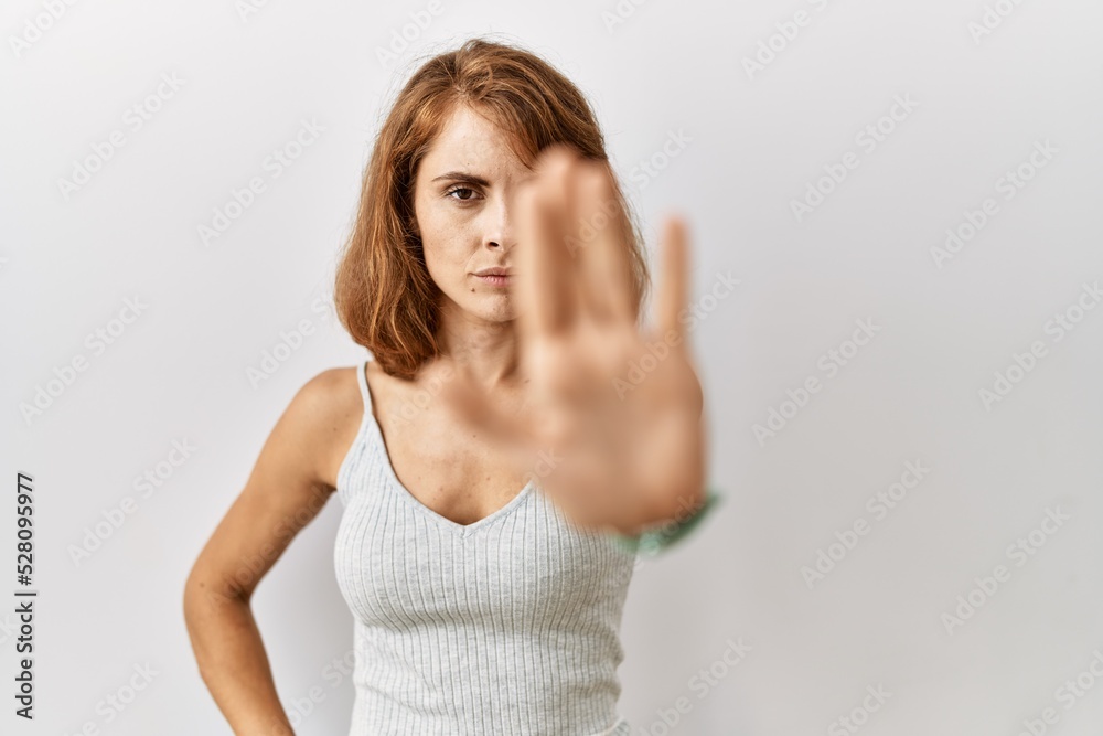 Beautiful caucasian woman standing over isolated background doing stop sing with palm of the hand. warning expression with negative and serious gesture on the face.