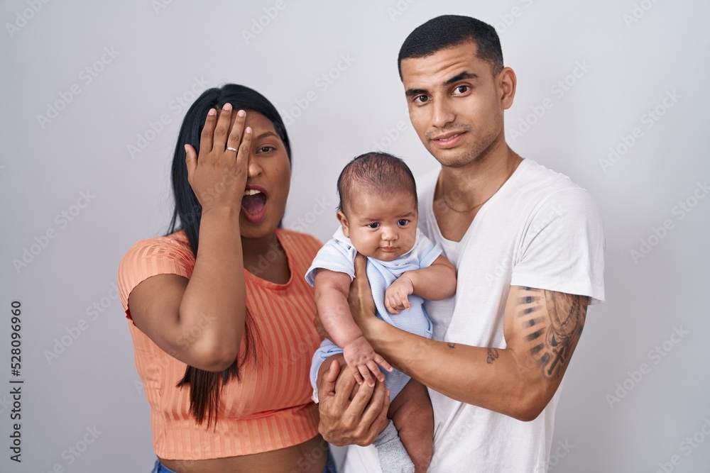 Young hispanic couple with baby standing together over isolated background yawning tired covering half face, eye and mouth with hand. face hurts in pain. Young hispanic couple with baby standing together over isolated background yawning tired covering half face, eye and mouth with hand. face hurts in pain.