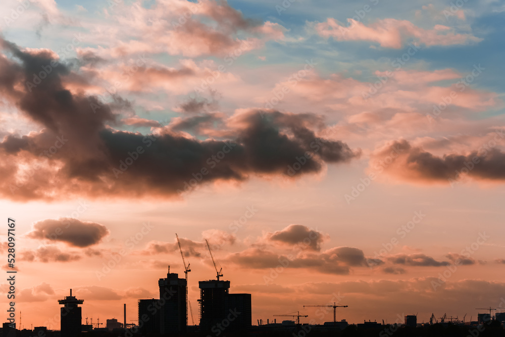 Black silhouette of city buildings in a line at sunset. Industrial urban landscape. Fantastic colorful dramatic sky. Copy space, postcard.