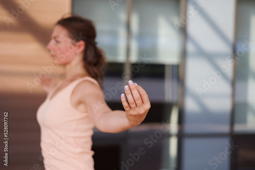 Beautiful strong muscular woman doing stretching on mat on terrace outdoors. Healthy young adult girl in sportswear stretch alone. Fit thin gimnast doing yoga and pilates, training on mat. Perspective