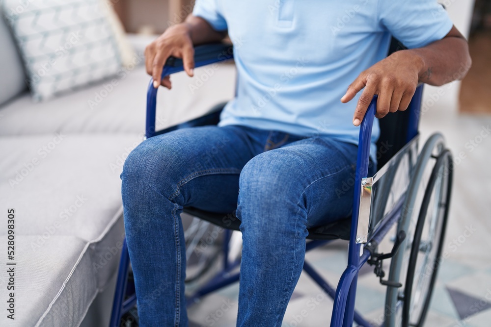 Obraz premium Young latin man sitting on wheelchair at home