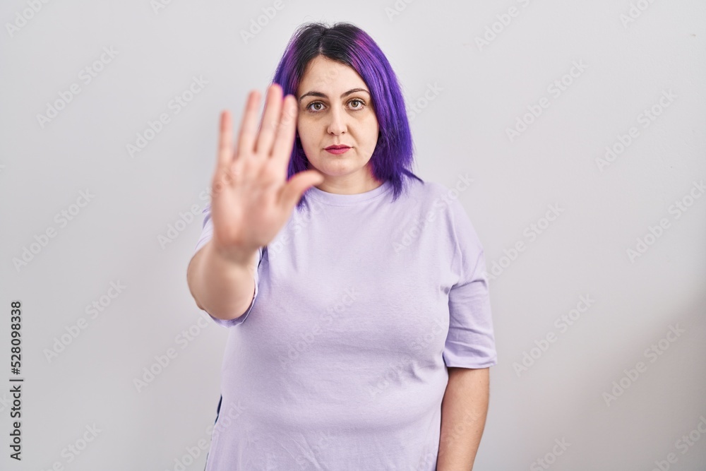 Plus size woman wit purple hair standing over isolated background doing stop sing with palm of the hand. warning expression with negative and serious gesture on the face. Plus size woman wit purple hair standing over isolated background doing stop sing with palm of the hand. warning expression with negative and serious gesture on the face.