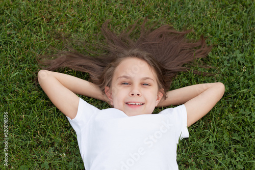 Portrait of a little girl lying on the green grass