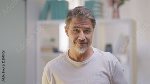 Portrait of happy, confident older man in casual white t-shirt, looking at camera, smiling. Mature age, middle age, mid adult casual man in 50s