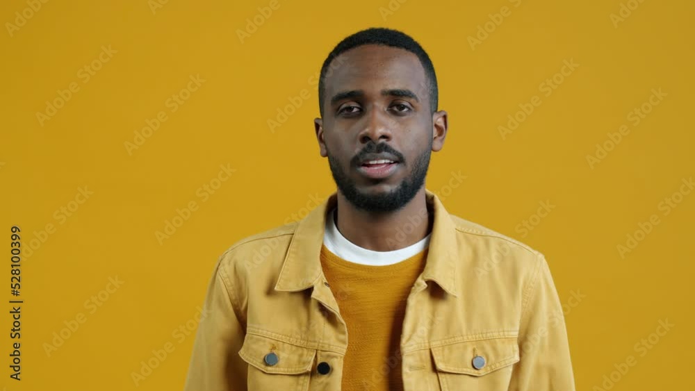 Portrait of sociable African American man pointing at camera and making Call me hand gesture with friendly smile standing on yellow background Portrait of sociable African American man pointing at camera and making Call me hand gesture with friendly smile standing on yellow background