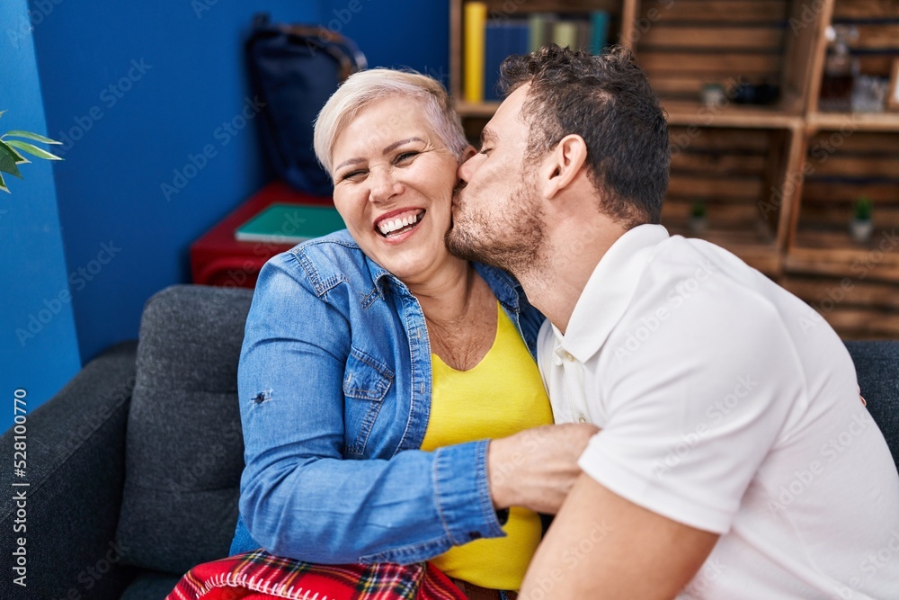 Obraz premium Mother and son sitting on sofa kissing at home