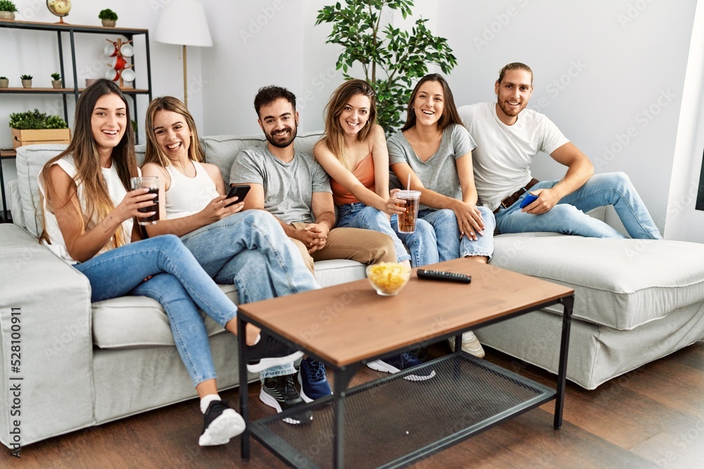 Group of young friends smiling happy and using smartphone sitting on the sofa at home.