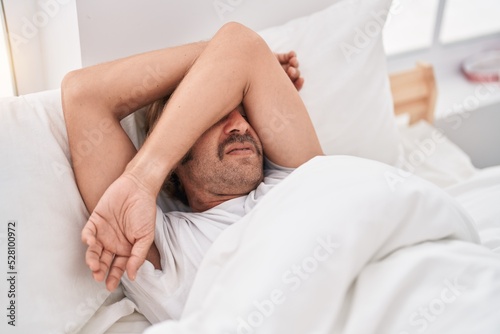 Young blond man stressed lying on bed at bedroom