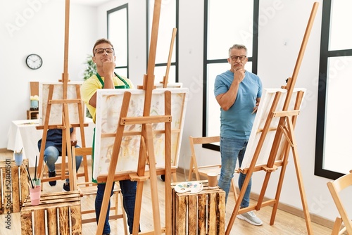 Group of middle age people artist at art studio serious face thinking about question with hand on chin, thoughtful about confusing idea