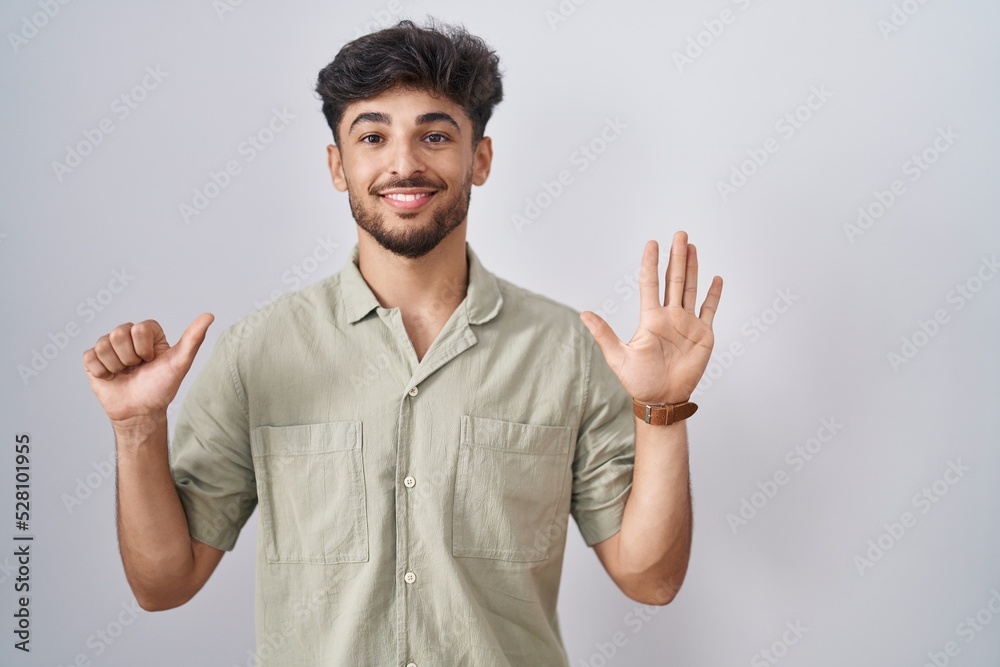 Arab man with beard standing over white background showing and pointing up with fingers number six while smiling confident and happy. Arab man with beard standing over white background showing and pointing up with fingers number six while smiling confident and happy.