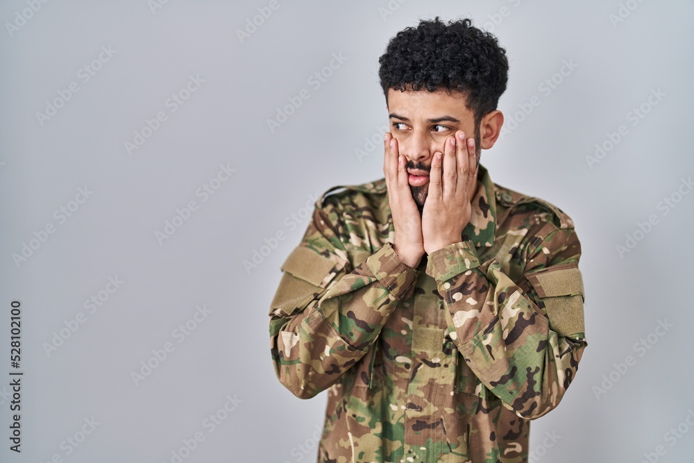 Arab man wearing camouflage army uniform tired hands covering face, depression and sadness, upset and irritated for problem