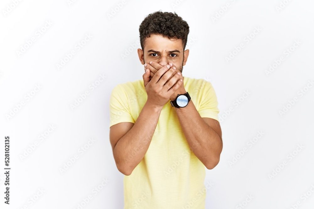 Arab young man standing over isolated background shocked covering mouth with hands for mistake. secret concept. Arab young man standing over isolated background shocked covering mouth with hands for mistake. secret concept.