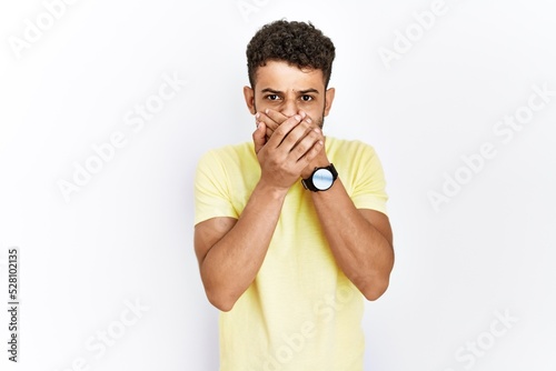 Arab young man standing over isolated background shocked covering mouth with hands for mistake. secret concept.