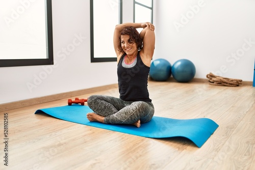 Wallpaper Mural Middle age hispanic sporty woman smiling happy stretching at sport center
