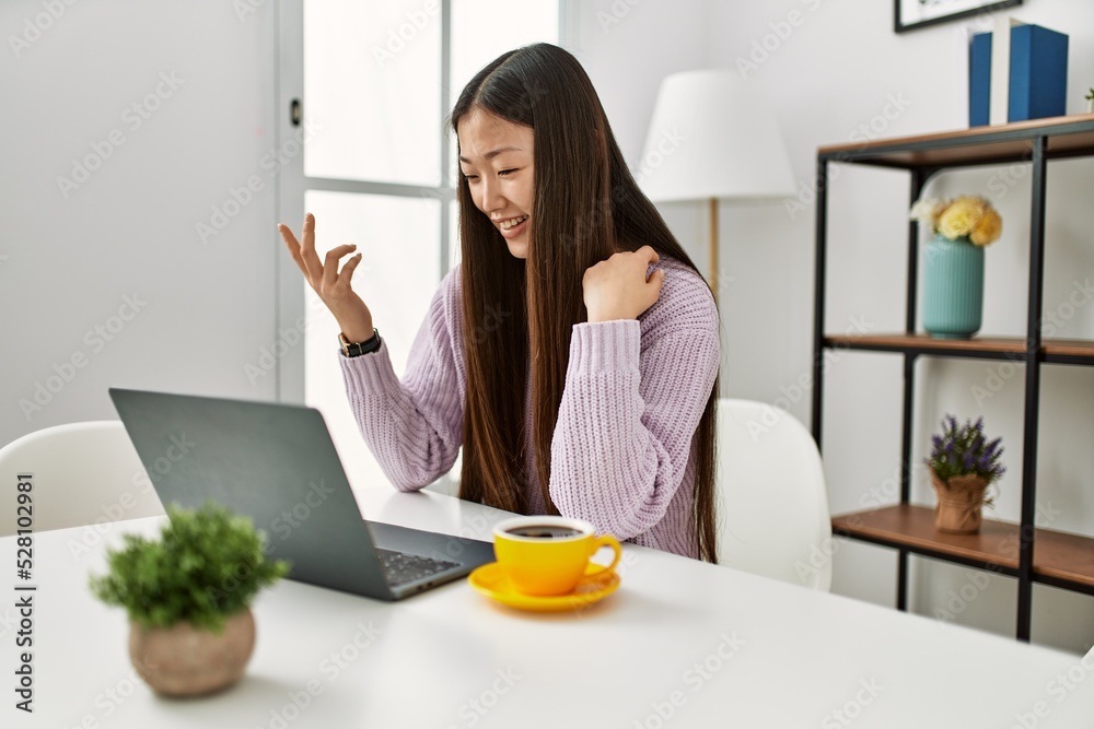 Young chinese girl having video call using laptop sitting on the table at home. Young chinese girl having video call using laptop sitting on the table at home.