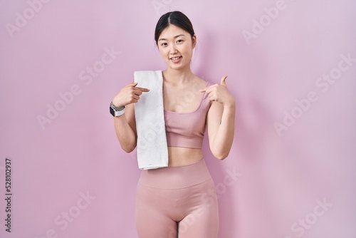 Chinese young woman wearing sportswear and towel looking confident with smile on face, pointing oneself with fingers proud and happy.