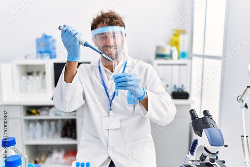 Young hispanic man wearing scientist uniform working at laboratory