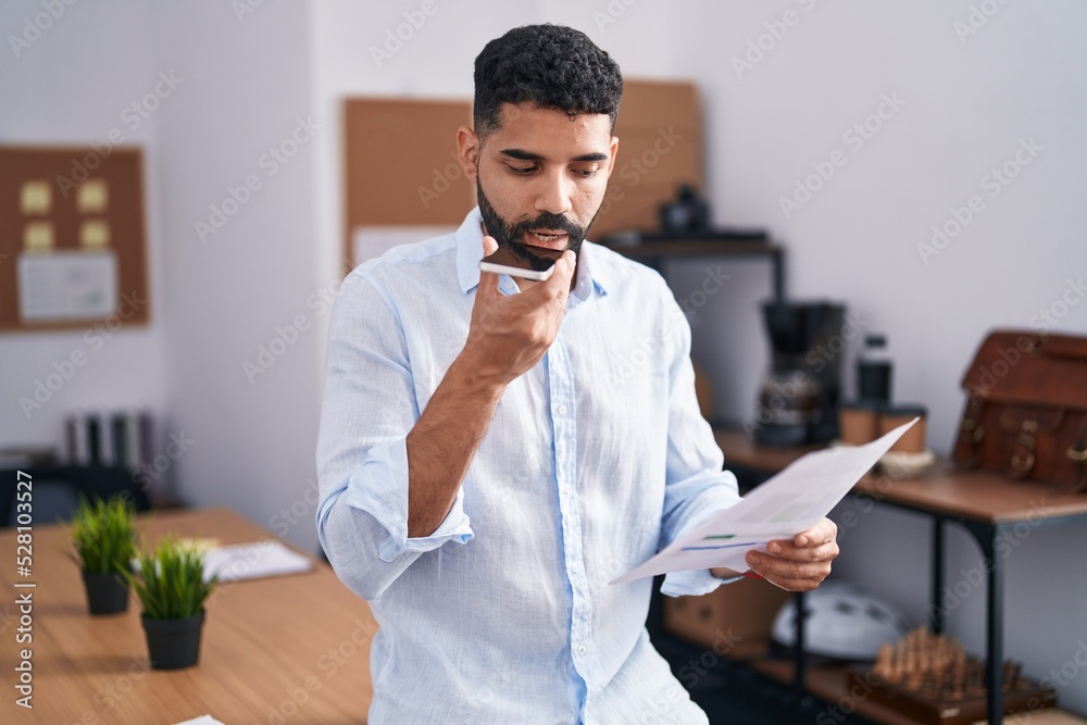 Young arab man business worker talking on smartphone reading document at office Young arab man business worker talking on smartphone reading document at office