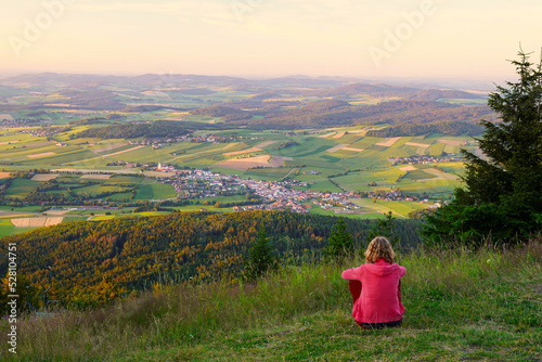 A woman sitting on mount Hohenbogen, looking to Neukirchen Heiligblut, a small town in the Bavarian Forest. photo