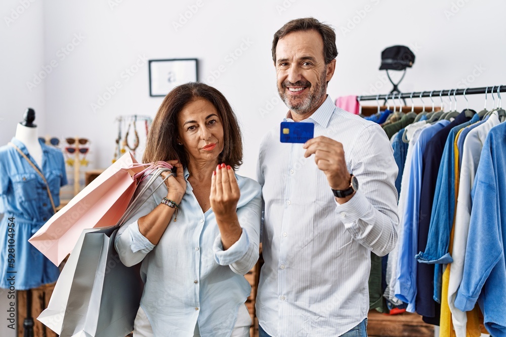 Hispanic middle age couple holding shopping bags and credit card doing italian gesture with hand and fingers confident expression Hispanic middle age couple holding shopping bags and credit card doing italian gesture with hand and fingers confident expression