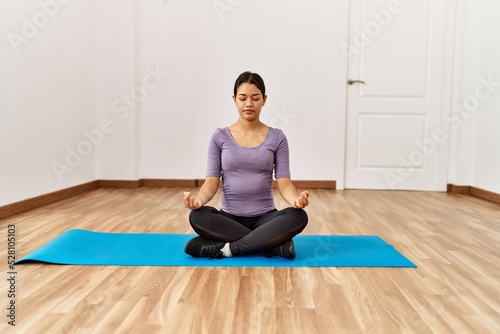 Young latin woman training yoga at sport center