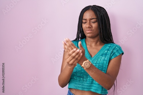 Young african american with braids standing over pink background suffering pain on hands and fingers  arthritis inflammation