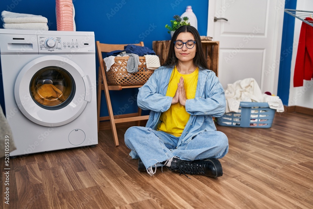 Young hispanic woman doing yoga exercise waiting for washing machine at laundry room Young hispanic woman doing yoga exercise waiting for washing machine at laundry room