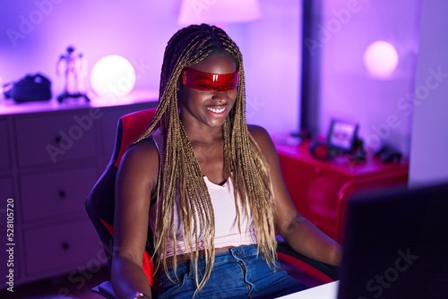 African american woman streamer playing video game using virtual reality glasses at gaming room photo