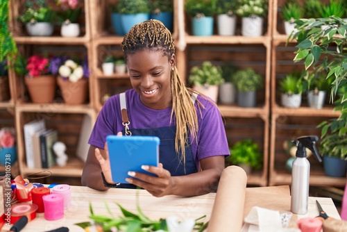 African american woman florist smiling confident using touchpad at florist