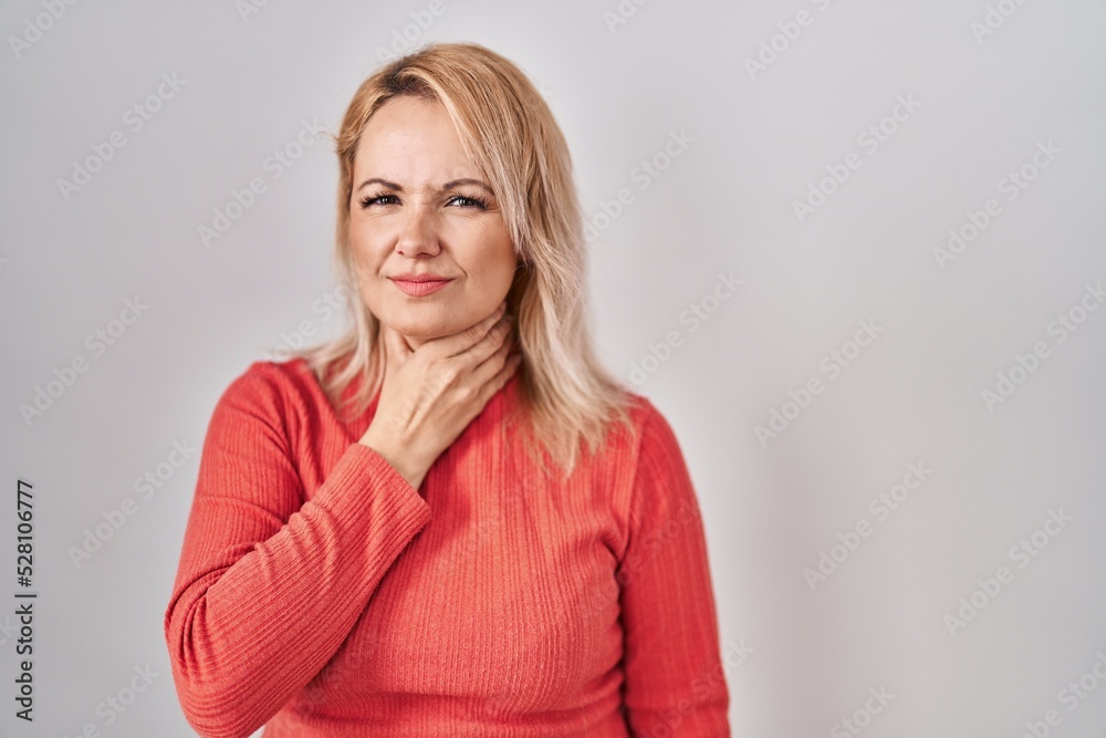Blonde woman standing over isolated background touching painful neck, sore throat for flu, clod and infection Blonde woman standing over isolated background touching painful neck, sore throat for flu, clod and infection