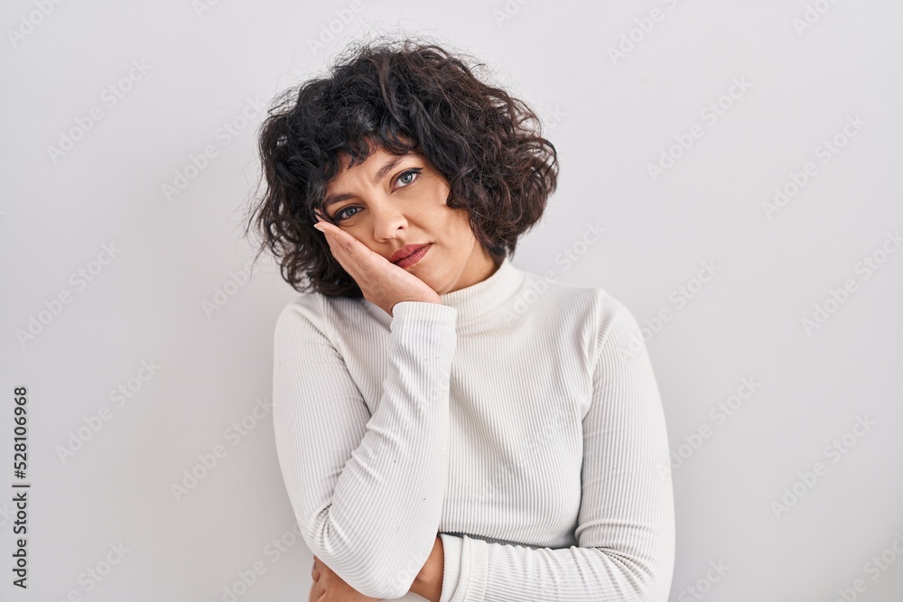 Hispanic woman with curly hair standing over isolated background thinking looking tired and bored with depression problems with crossed arms. Hispanic woman with curly hair standing over isolated background thinking looking tired and bored with depression problems with crossed arms.