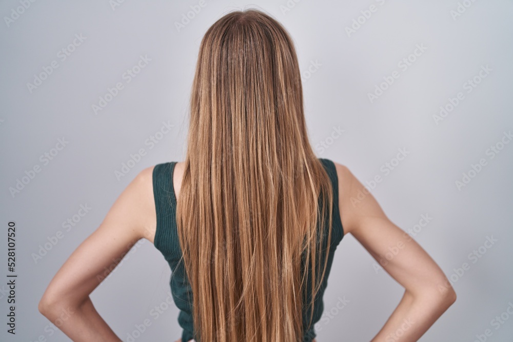 Young caucasian woman standing over white background standing backwards looking away with arms on body Young caucasian woman standing over white background standing backwards looking away with arms on body