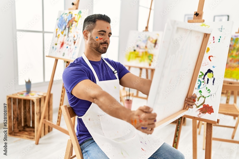 Young hispanic man holding draw canvas at art studio Young hispanic man holding draw canvas at art studio