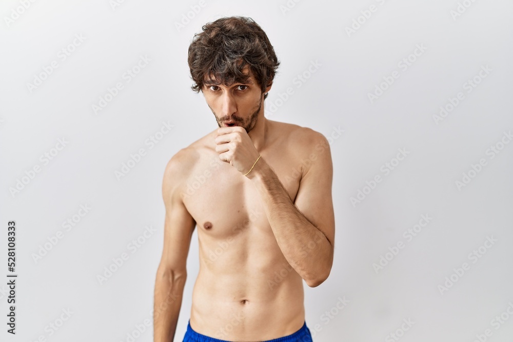 Fototapeta premium Young hispanic man standing shirtless over isolated, background feeling unwell and coughing as symptom for cold or bronchitis. health care concept.