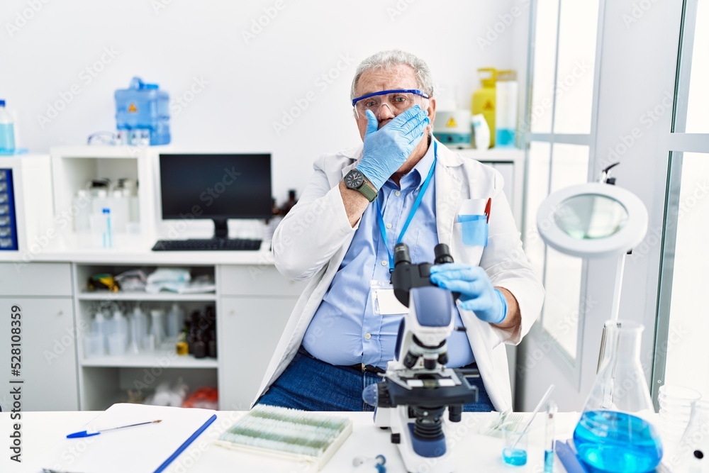 Senior caucasian man working at scientist laboratory shocked covering mouth with hands for mistake. secret concept. Senior caucasian man working at scientist laboratory shocked covering mouth with hands for mistake. secret concept.