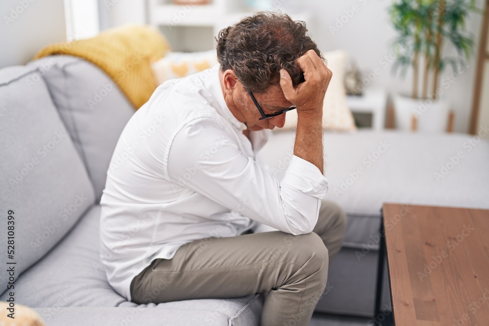 Middle age man stressed sitting on sofa at home