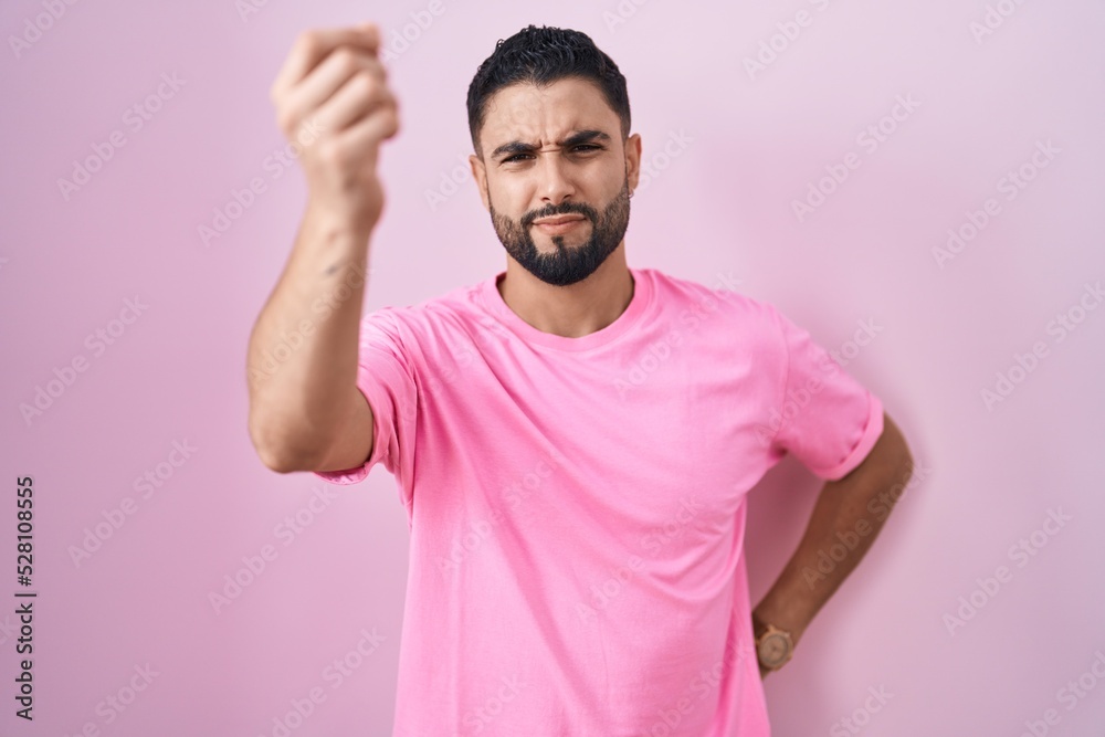 Hispanic young man standing over pink background doing italian gesture with hand and fingers confident expression Hispanic young man standing over pink background doing italian gesture with hand and fingers confident expression