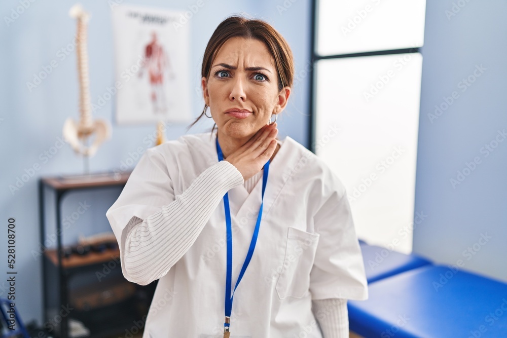 Young brunette woman working at pain recovery clinic cutting throat with hand as knife, threaten aggression with furious violence Young brunette woman working at pain recovery clinic cutting throat with hand as knife, threaten aggression with furious violence