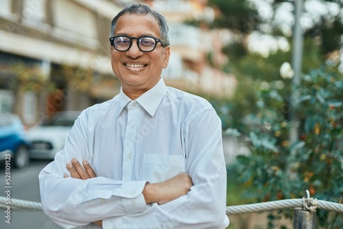 Middle age southeast asian man smiling confident with crossed arms at the city