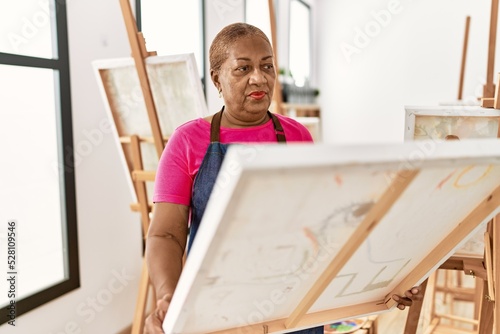 Senior african american woman looking draw canvas at art studio