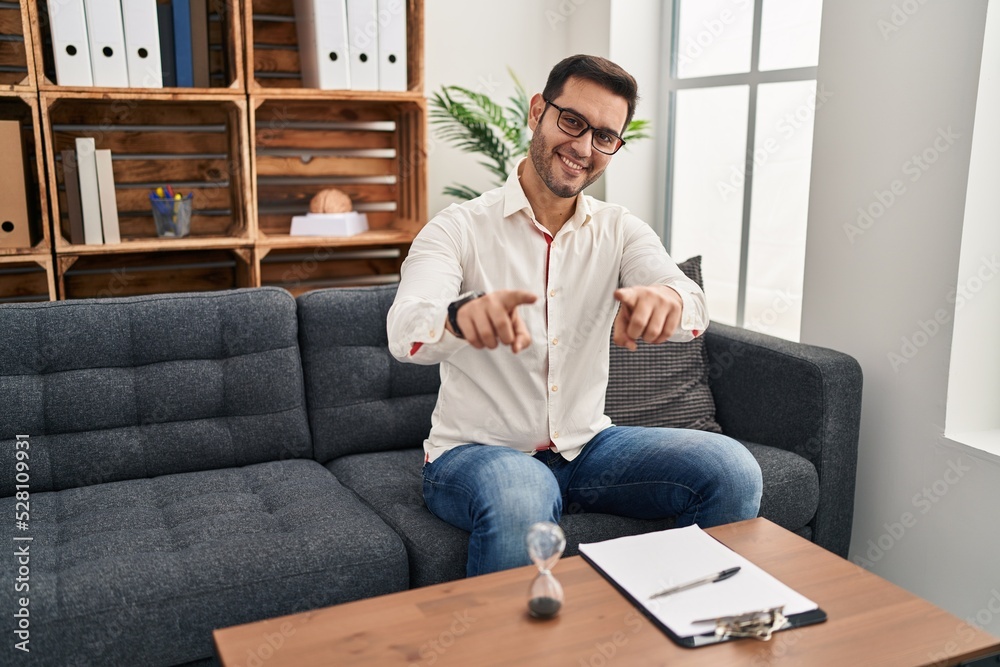 Young hispanic man with beard working at consultation office pointing to you and the camera with fingers, smiling positive and cheerful Young hispanic man with beard working at consultation office pointing to you and the camera with fingers, smiling positive and cheerful