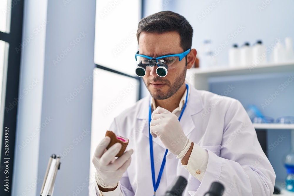 Young hispanic man scientist looking gemstone by magnifying glasses at laboratory Young hispanic man scientist looking gemstone by magnifying glasses at laboratory