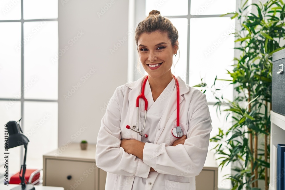 Young blonde woman wearing doctor uniform standing with arms crossed gesture at clinic Young blonde woman wearing doctor uniform standing with arms crossed gesture at clinic