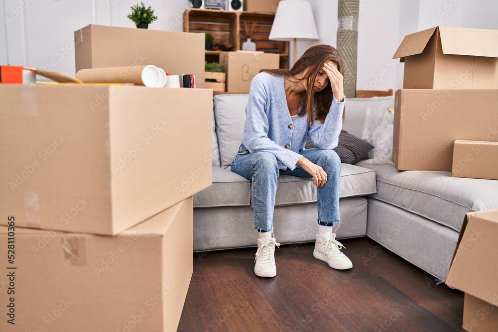 Young woman with worried expression sitting on sofa at new home Young woman with worried expression sitting on sofa at new home